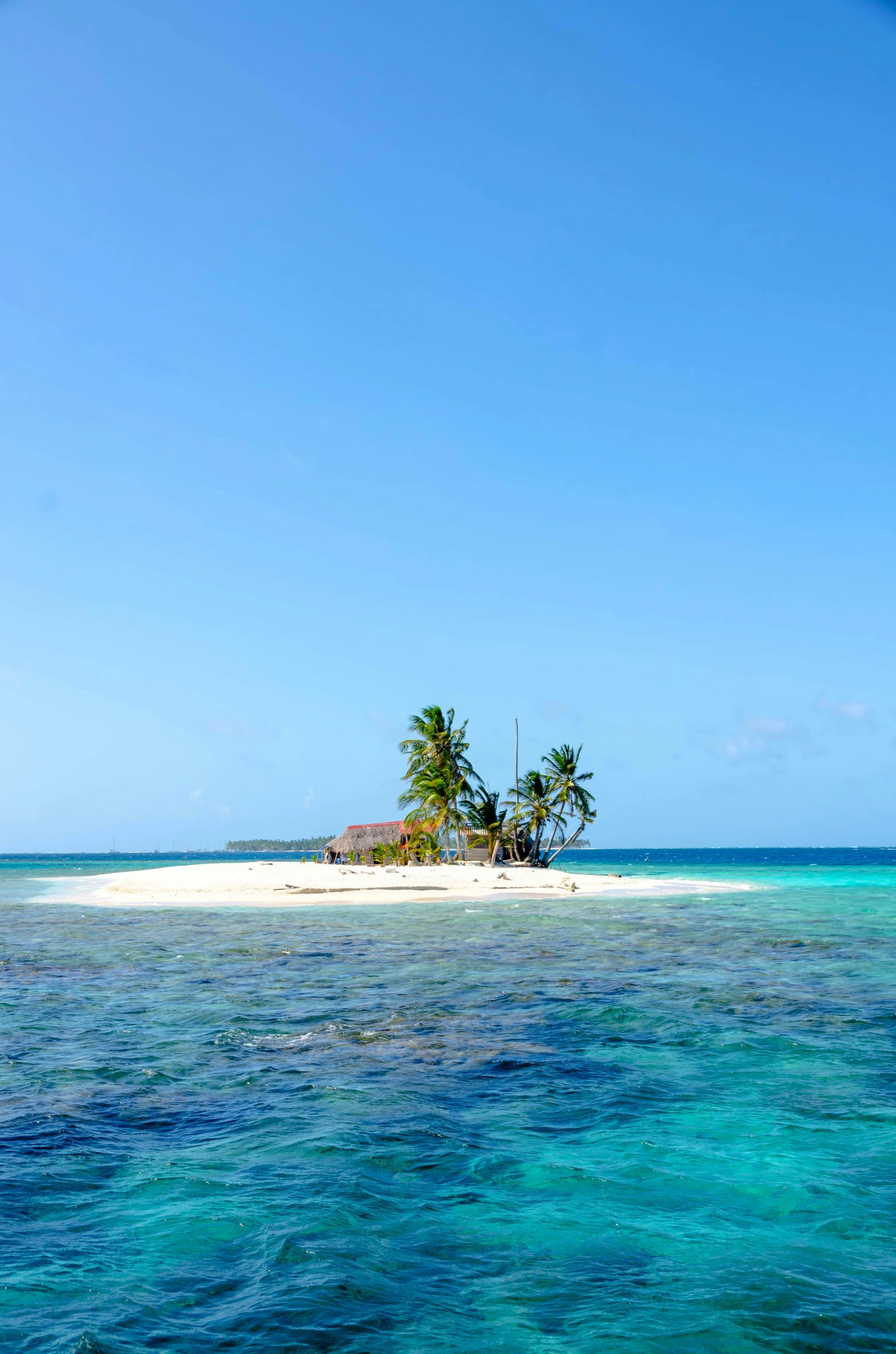 a small island in the middle of the ocean, white sandy beach, exterior, clear blue skies, paradisiac