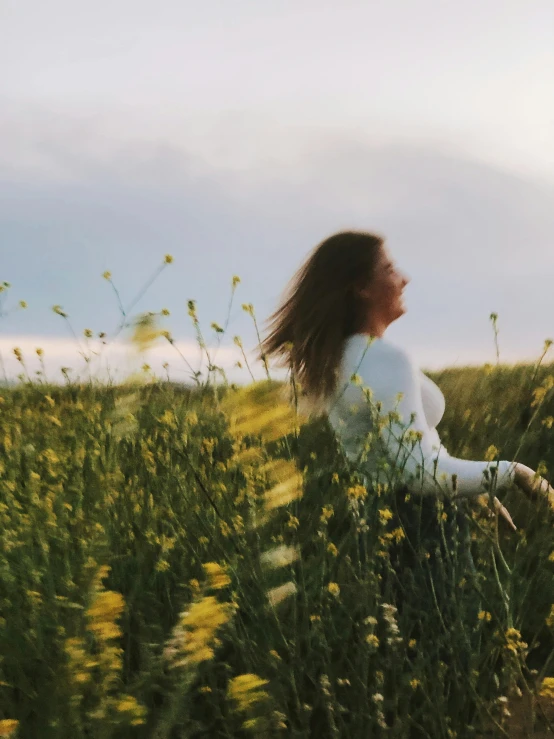 a woman sitting in a field of yellow flowers, by Christen Dalsgaard, trending on unsplash, hair waving in the wind, profile image, running freely, low quality photo