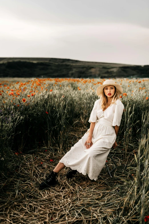 a woman sitting in a field of flowers, a portrait, inspired by Elsa Bleda, unsplash contest winner, white straw flat brimmed hat, poppy, high quality photo, coast