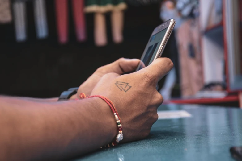 a close up of a person holding a cell phone, a tattoo, trending on pexels, avatar image, colour photo, geometry, photo for a store