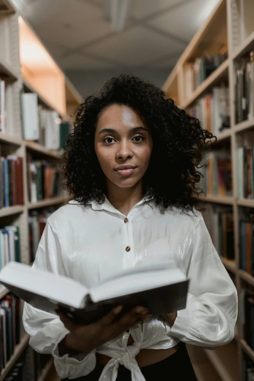 a woman holding a book in a library, a portrait, pexels contest winner, a black man with long curly hair, gif, symmetrical centered portrait, abcdefghijklmnopqrstuvwxyz