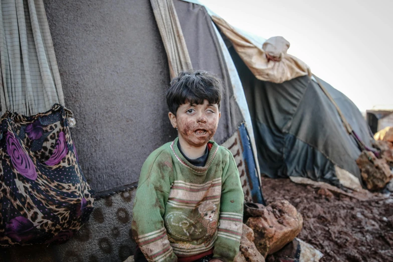 a young boy sitting on top of a pile of dirt, pexels contest winner, hurufiyya, her face is covered with mud, tents, real life photo of a syrian man, soup