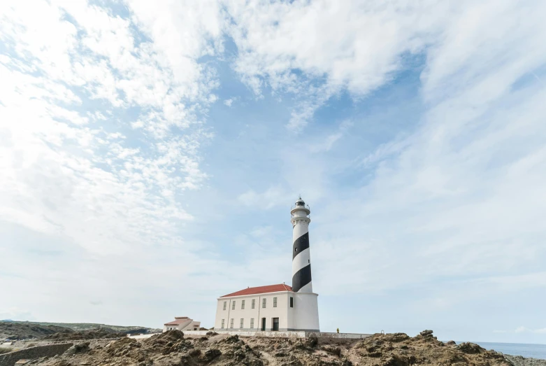 a lighthouse sitting on top of a rocky beach, pexels contest winner, modernism, antoni gaudi, square, white, silo