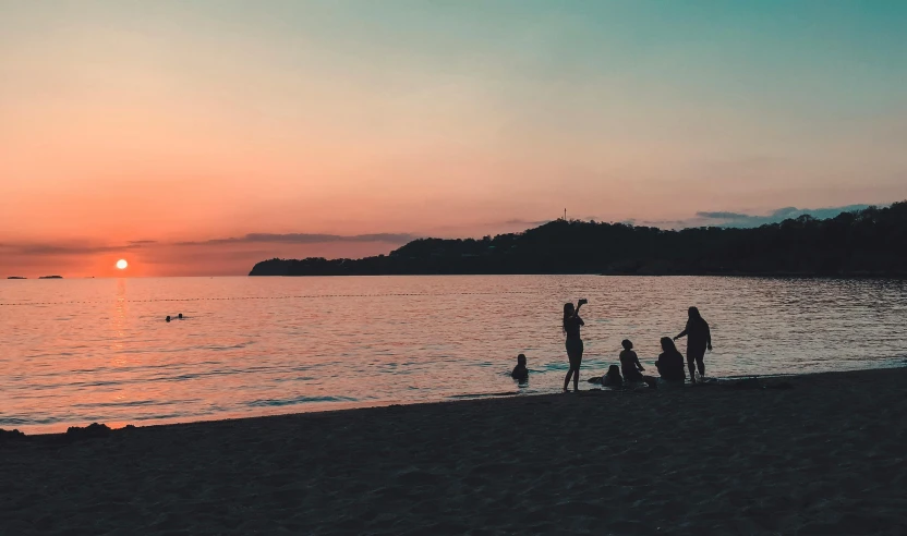 a group of people standing on top of a sandy beach, by Carey Morris, pexels contest winner, relaxing on the beach at sunset, split near the left, children playing at the beach, slightly pixelated