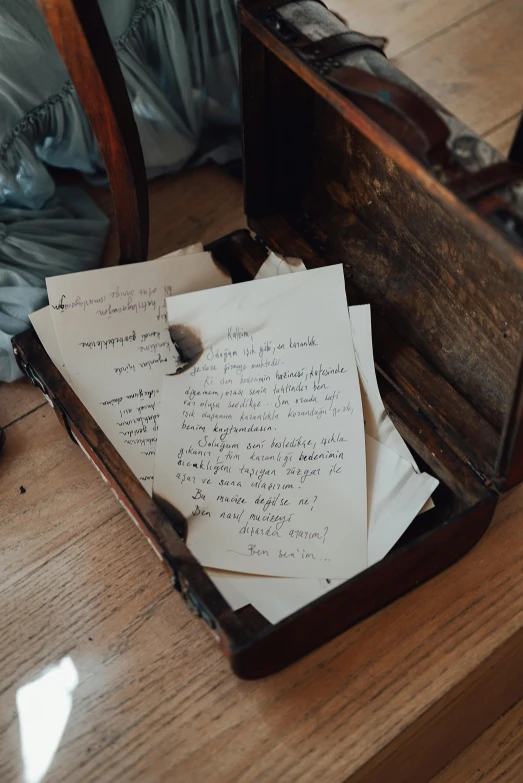 an open suitcase sitting on top of a wooden floor, an album cover, by Jessie Algie, unsplash, visual art, with some hand written letters, museum artifact, swedish writing, holding grimoire