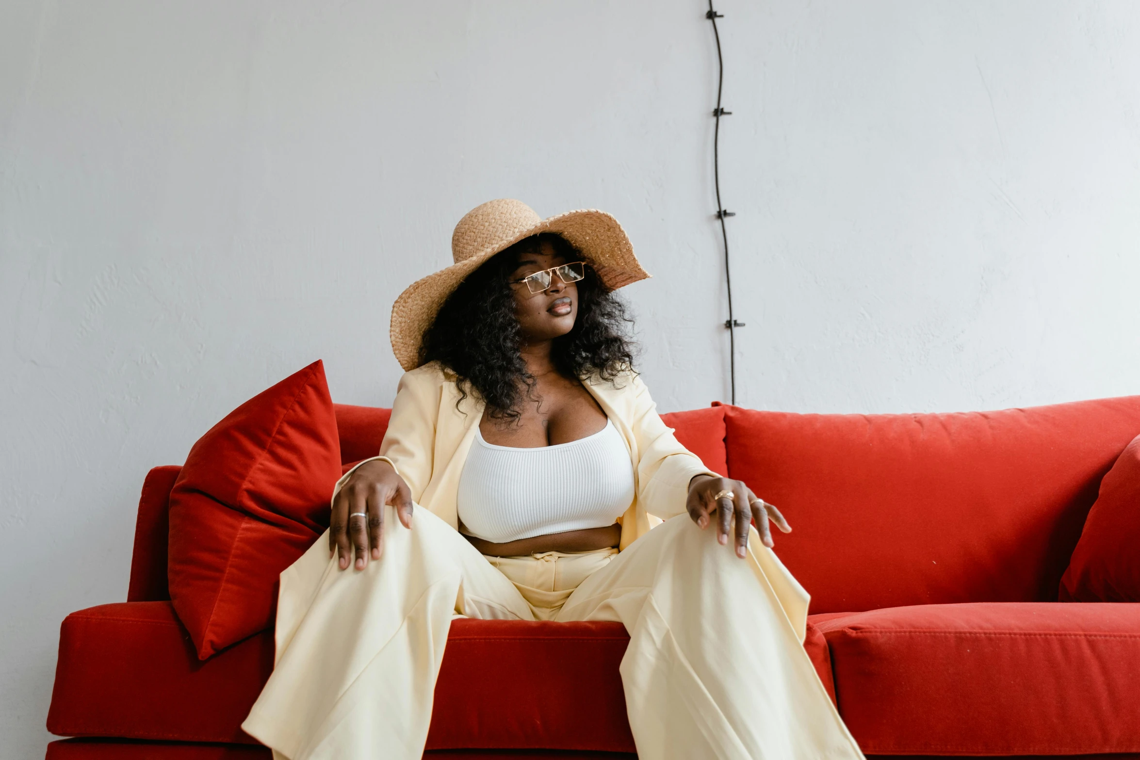 a woman sitting on top of a red couch, by Carey Morris, pexels contest winner, beige fedora, afro, yellow clothes, thicc