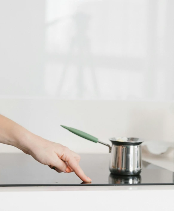 a close up of a person cooking on a stove, pexels contest winner, minimalism, holding wand, ☕ on the table, plain background, with pointing finger