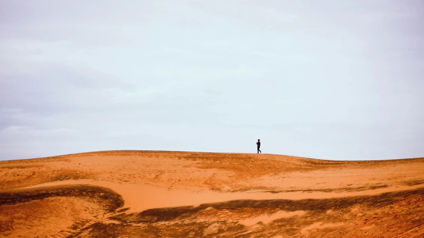 a person standing on top of a sandy hill, inspired by Scarlett Hooft Graafland, unsplash contest winner, minimalism, australian outback, running freely, tiny person watching, conde nast traveler photo