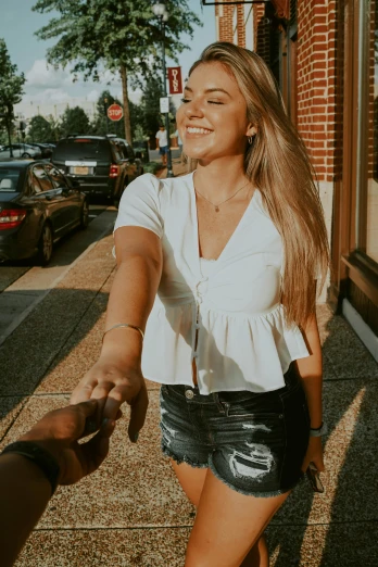 a woman holding a man's hand while walking down the street, trending on pexels, happening, wearing a cute top, smiling down from above, snapchat photo, beautiful blonde girl