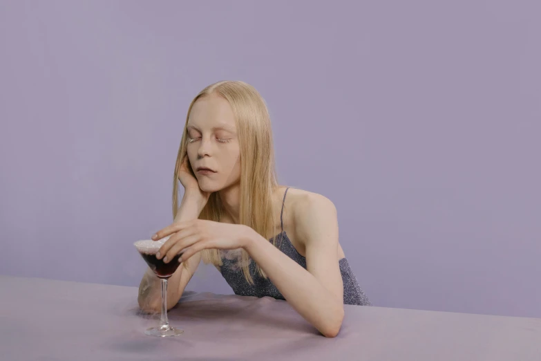 a woman sitting at a table with a glass of wine, an album cover, tumblr, magic realism, pale skin and purple eyes, julia hetta, ignant, still from l'estate
