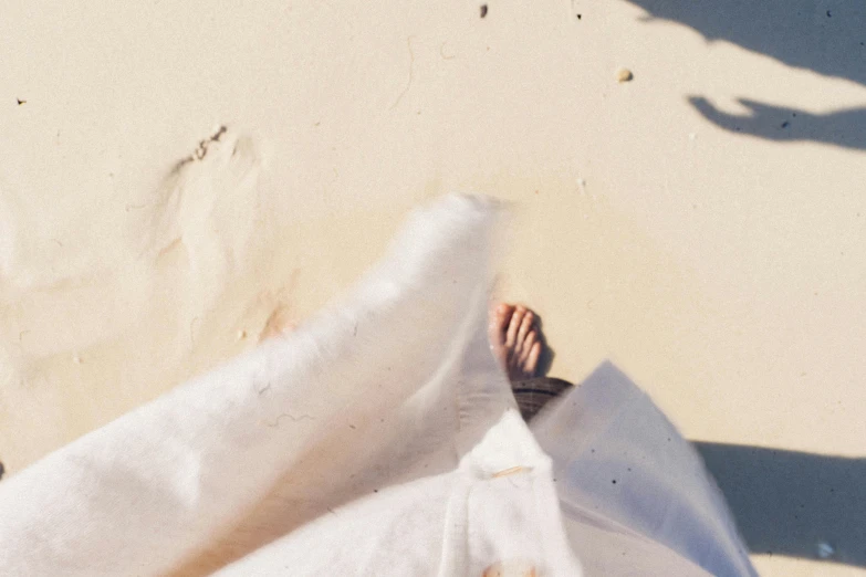 a person standing on top of a sandy beach, trending on unsplash, figuration libre, white cloth, lying on an abstract, linen, flatlay