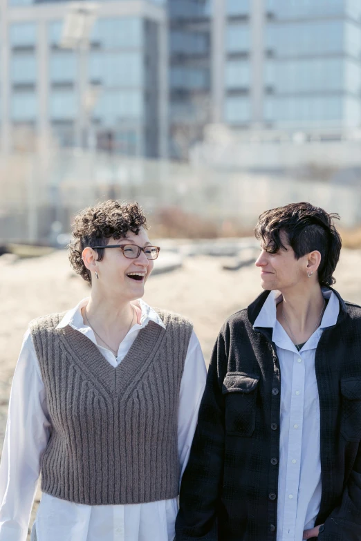 a couple of people standing next to each other, an album cover, by Harriet Zeitlin, lesbian, shoreline, taken in 2 0 2 0, smiling at each other