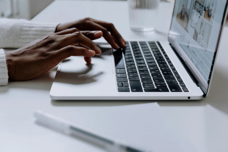 a close up of a person typing on a laptop, a computer rendering, by Carey Morris, pexels, afro tech, on a white table, low-angle shot, unedited