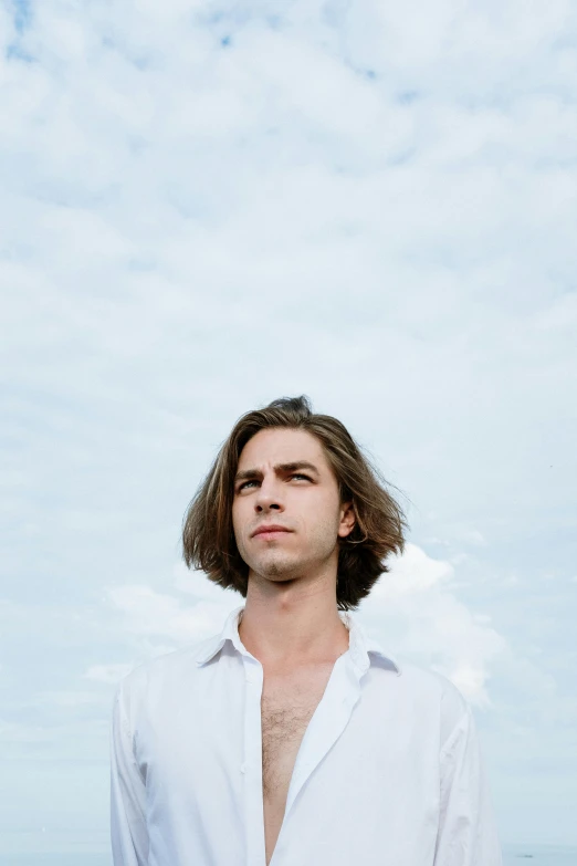 a man standing on top of a beach next to the ocean, an album cover, inspired by Alexander Kanoldt, trending on unsplash, renaissance, shoulder-length hair, portrait of archie andrews, white sky, headshot photo