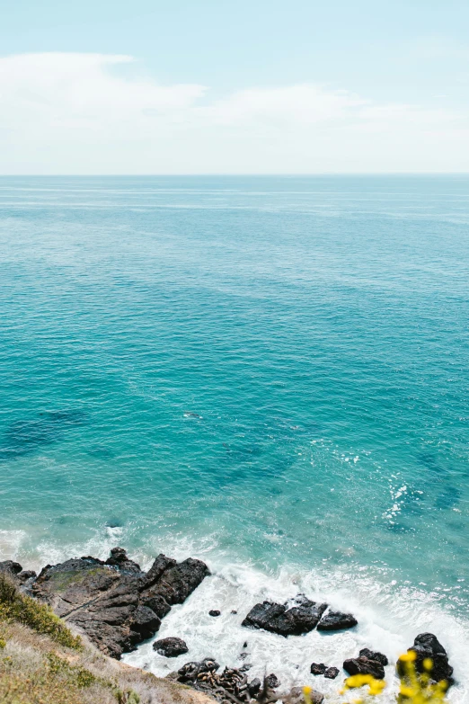 a yellow fire hydrant sitting on the side of a cliff next to the ocean, pexels contest winner, minimalism, teal palette, malibu canyon, view from above on seascape, today's featured photograph 4k