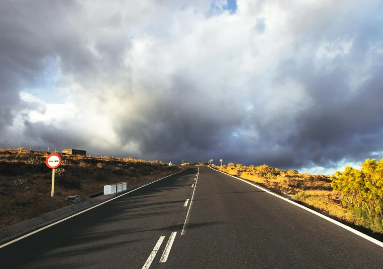 an empty road with a cloudy sky in the background, unsplash, reunion island, be running up that hill, yellow clouds, wet asphalt