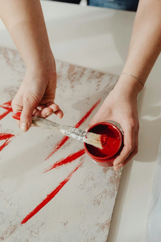 a person painting with red paint on a piece of paper, inspired by James Rosenquist, trending on pexels, action painting, bleeding in the bath, lacquerware, red and white stripes, red carpeted floor