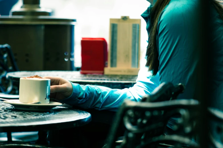 a woman sitting at a table with a cup of coffee, inspired by Elsa Bleda, private press, aussie baristas, videogame still, medium closeup, blue