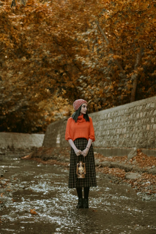 a woman standing in the middle of a river, inspired by Oleg Oprisco, pexels contest winner, renaissance, holding a jack - o - lantern, tartan hoodie, clothed in ancient street wear, ( 3 1