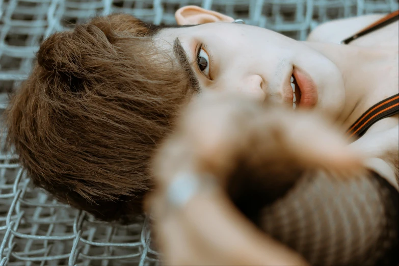a young man laying on top of a metal floor, trending on pexels, hyperrealism, wan adorable korean face, androgynous face, brown haired, video