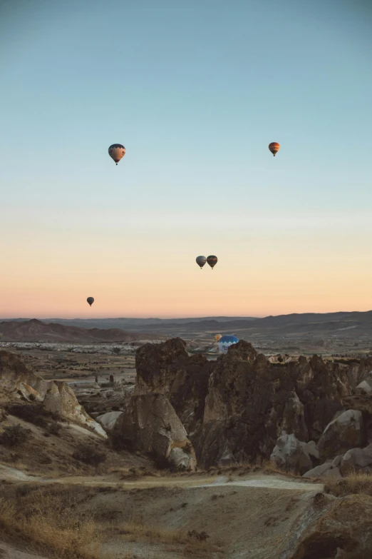 a group of hot air balloons flying in the sky, unsplash contest winner, turkey, rock arcs, late summer evening, color”