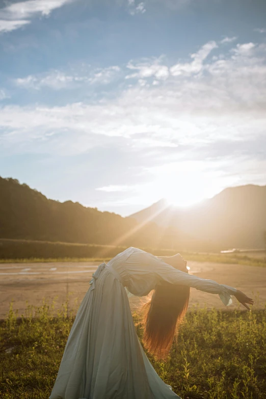 a woman is doing a handstand in a field, unsplash, renaissance, taiwan, low sun, flowing robe, sunset in a valley