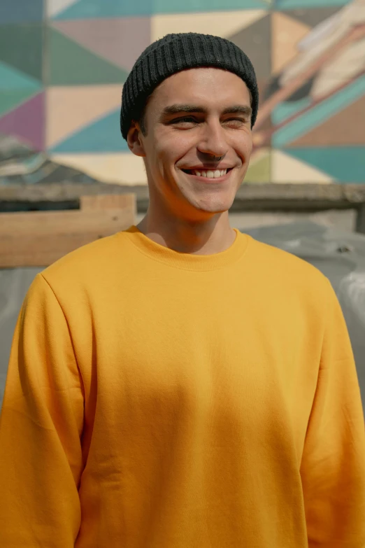 a man in a yellow shirt and a black hat, pexels contest winner, wearing sweatshirt, loosely cropped, short smile, large and tall