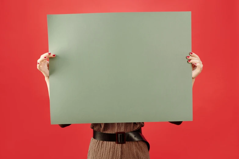 a woman holding a sign in front of her face, by Paul Bird, postminimalism, sage green, high quality product photo, matte surface, green bright red