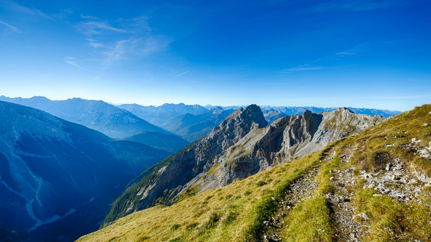 a view of the mountains from the top of a mountain, by Otto Meyer-Amden, pexels contest winner, les nabis, clear blue skies, hiking trail, brown, slide show