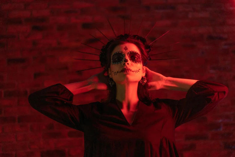 a woman standing in front of a brick wall, pexels contest winner, gothic art, ( el dia los muertos ), high red lights, crown made of bones, disco club of the occult