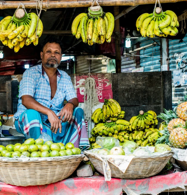 a man sitting in front of a fruit stand, pexels contest winner, sri lanka, square, on a bright day, vibrantly lush