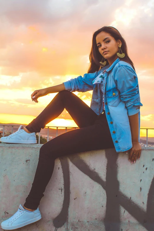 a woman sitting on top of a cement wall, by Niko Henrichon, pexels contest winner, isabela moner, sunset!, wearing a jeans jackets, beautiful city black woman only