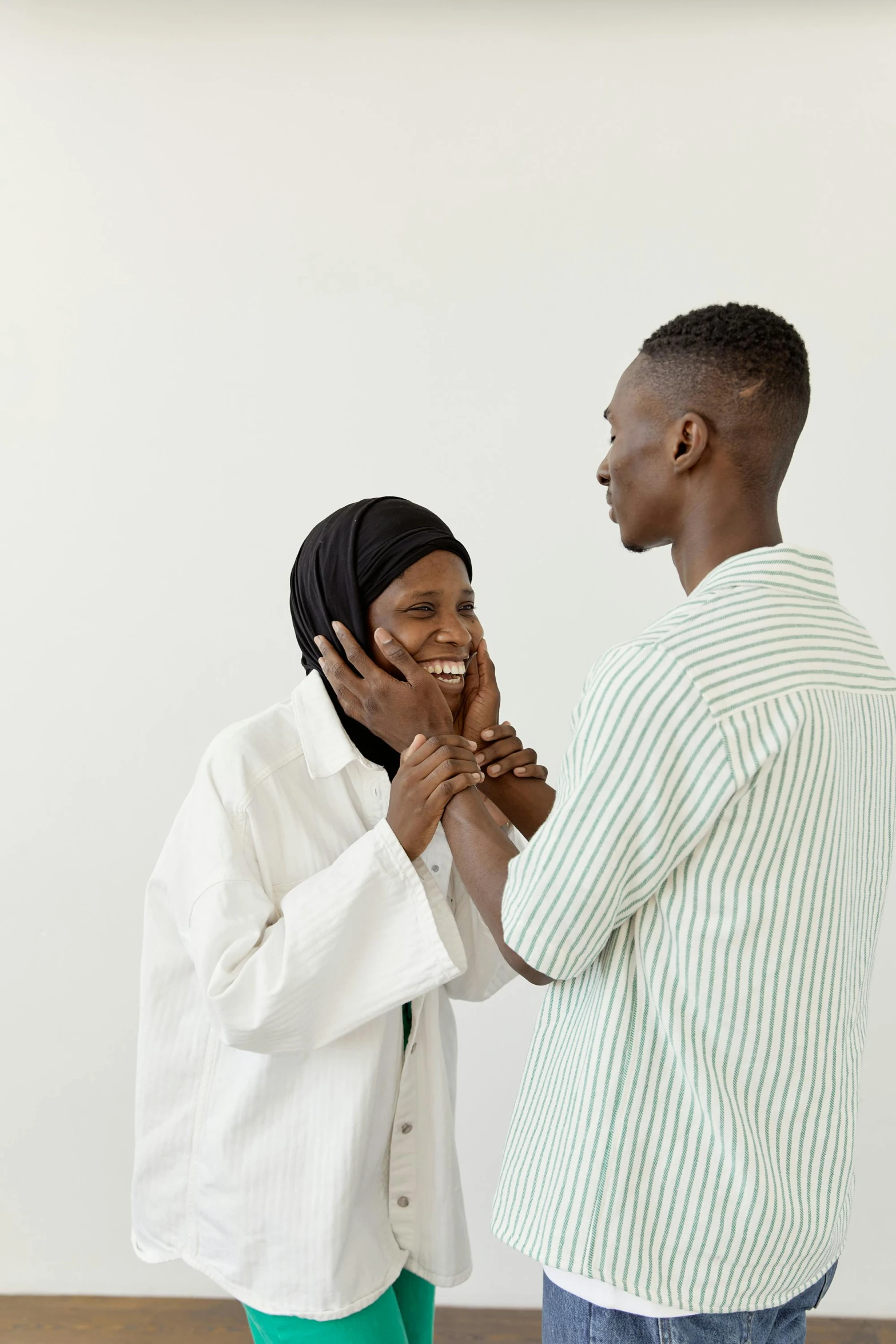 a man and a woman standing next to each other, pexels contest winner, hurufiyya, reaching out to each other, male physician, mutahar laughing, plain background