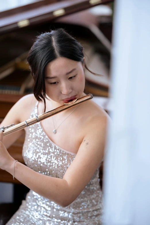 a woman in a silver dress playing a flute, inspired by Zheng Xie, unsplash, yanjun chengt, on a white table, a young asian woman, middle close up