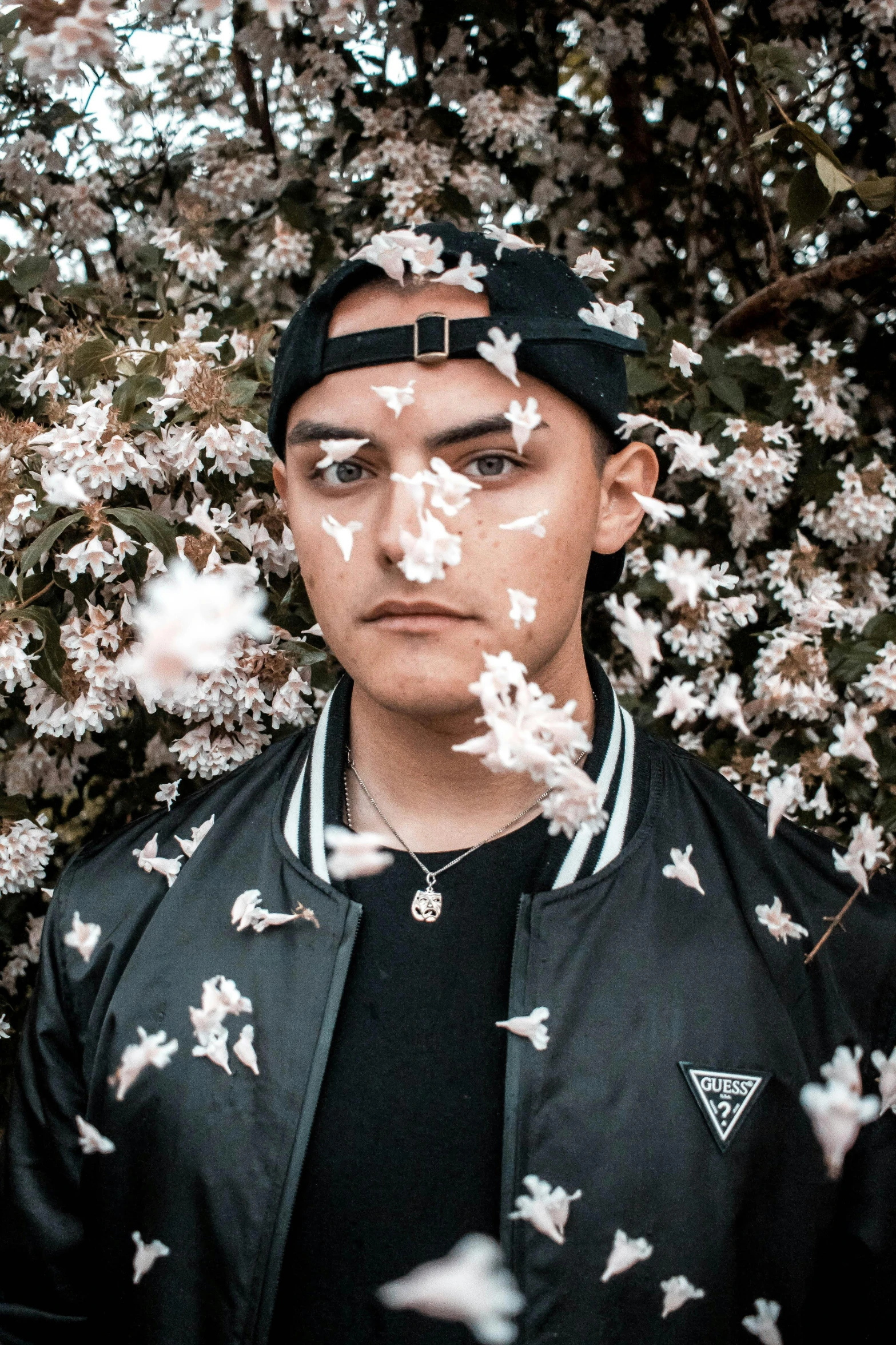 a man standing in front of a flowering tree, an album cover, inspired by Kyle Lambert, trending on pexels, perfectly lit face, justin sun, ear floof, raphael personnaz