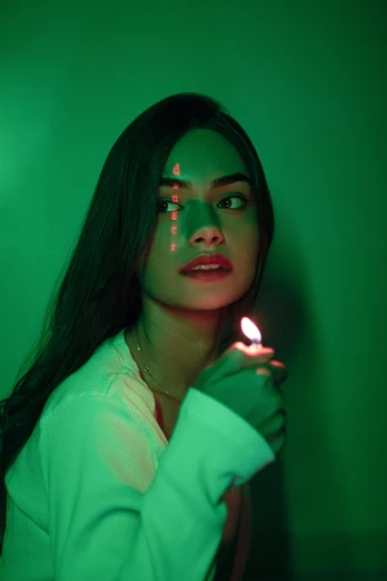 a woman holding a lit candle in her hand, a picture, inspired by Elsa Bleda, trending on pexels, surrealism, green face, asian girl, made of glowing oil, red green