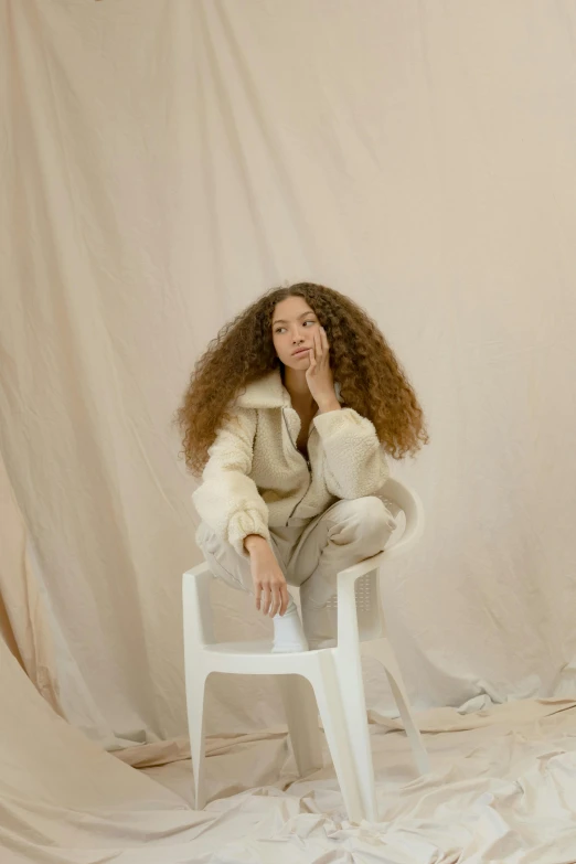 a woman sitting on top of a white chair, trending on pexels, renaissance, long curly fur, wearing a track suit, neutral light, bella poarch