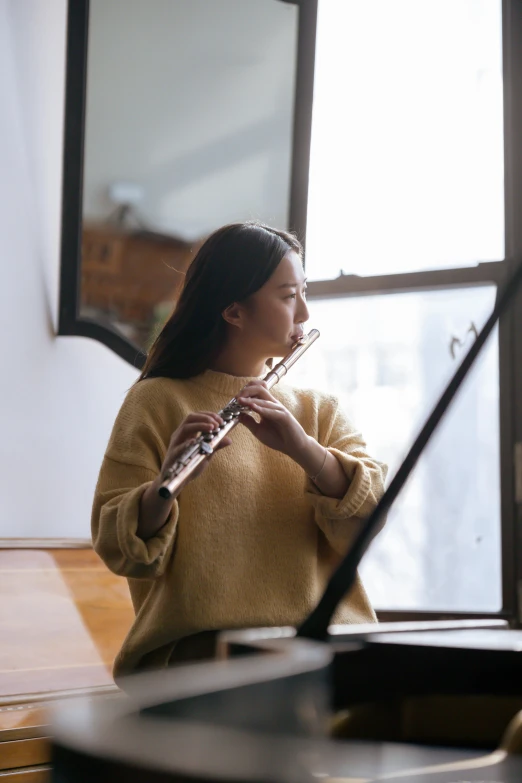 a woman playing a flute in front of a window, pexels contest winner, studying in a brightly lit room, australian, band playing, a young asian woman
