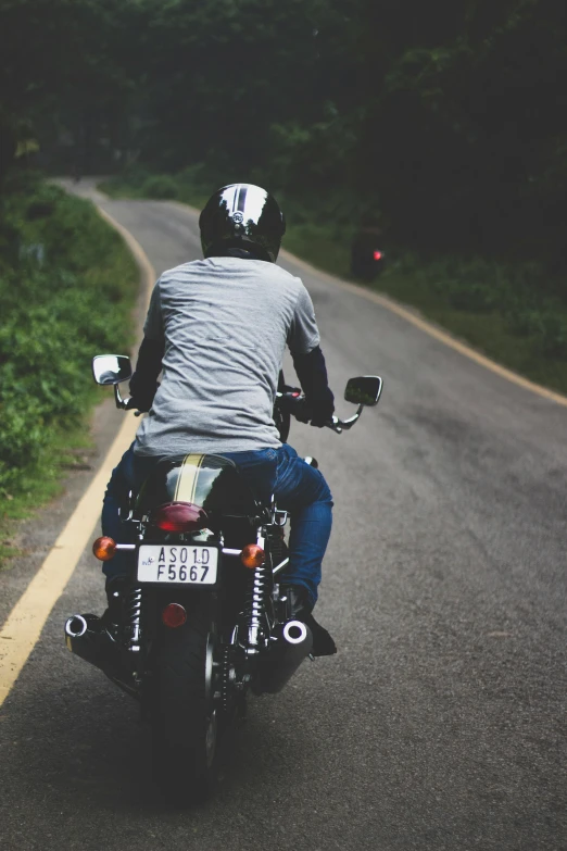 a man riding on the back of a motorcycle down a road, pexels contest winner, wearing a round helmet, sri lanka, profile image, back facing
