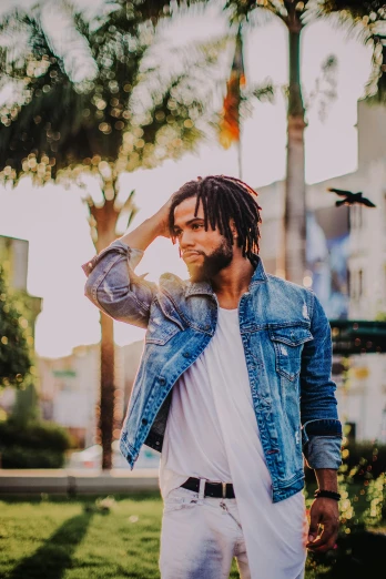 a man wearing a denim jacket and white pants, pexels contest winner, dreadlock black hair, palm trees in the background, (golden hour), hollywood standard