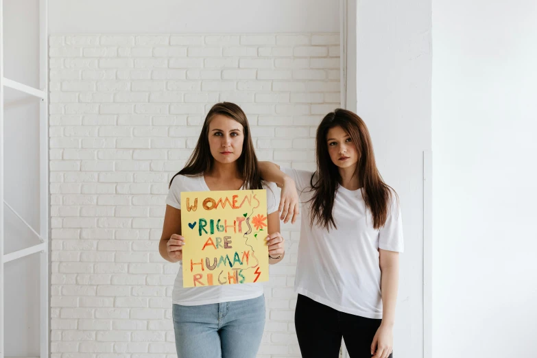 two women standing next to each other holding a sign, trending on pexels, roomies, profile image, high quality artwork, fights