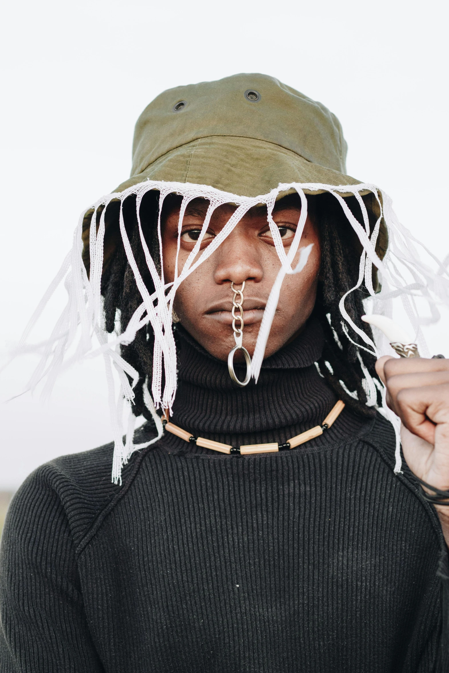 a close up of a person wearing a hat, trending on pexels, afrofuturism, ropes and chains, wearing turtleneck, torn clothing, rasta