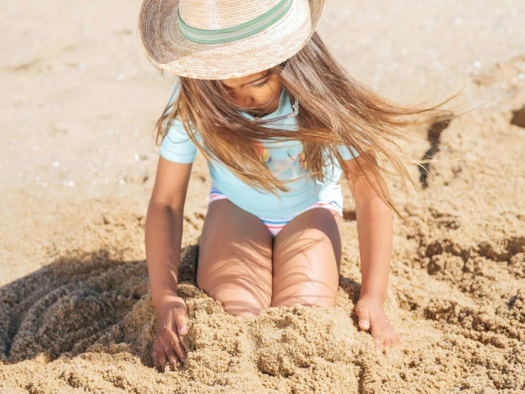 a little girl playing in the sand at the beach, by Arabella Rankin, unsplash, figuration libre, wearing straw hat, tan skin a tee shirt and shorts, her tiny hands are on her thighs, ilustration