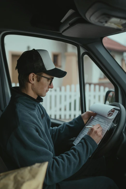 a man sitting in the driver's seat of a truck reading a paper, avatar image, jovana rikalo, high quality image