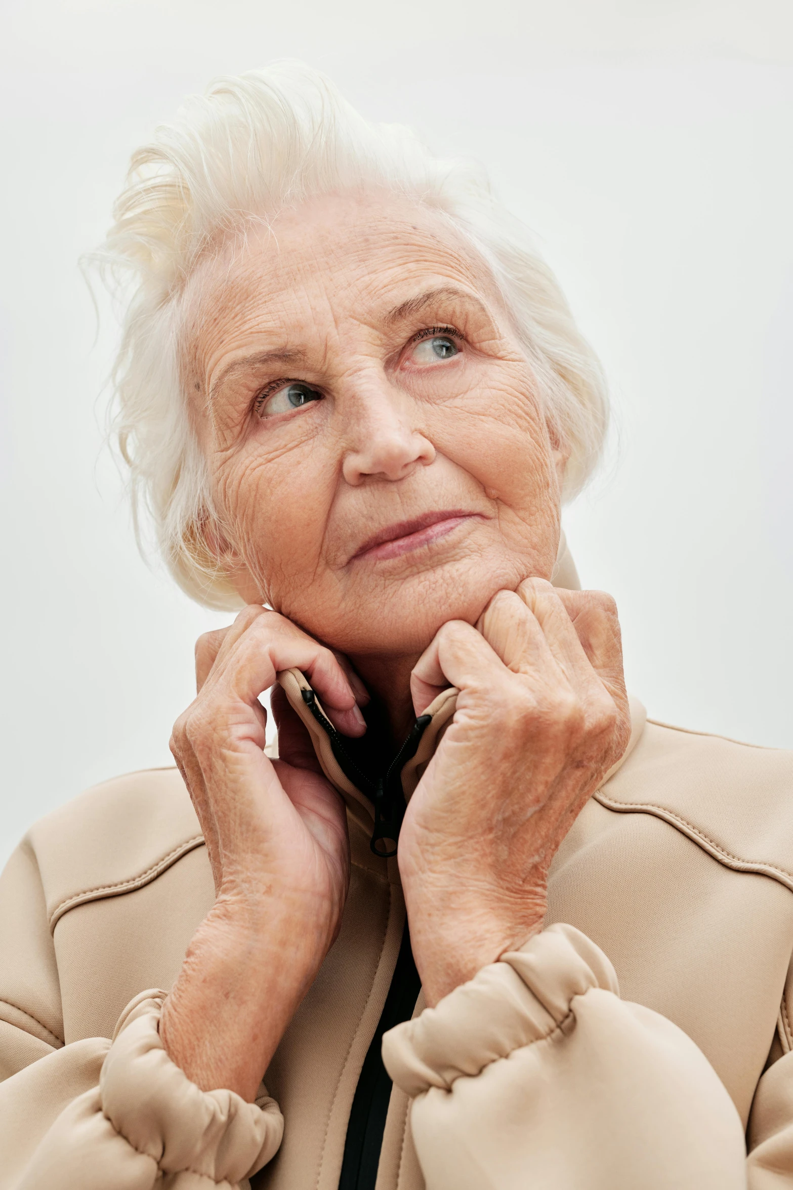 an older woman talking on a cell phone, inspired by Margareta Sterian, trending on unsplash, photorealism, wearing jacket, looking upwards, high cheekbones, plain background