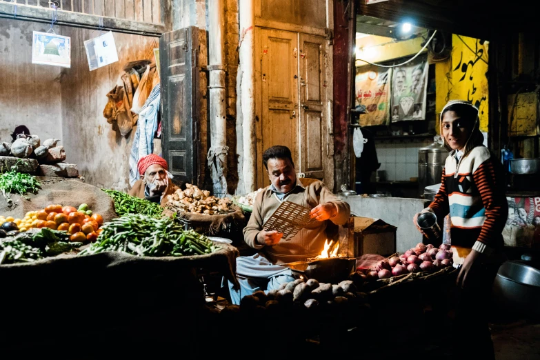 a group of people standing around a vegetable stand, by Julia Pishtar, pexels contest winner, talaat harb square cairo, lit up, on an indian street, profile image