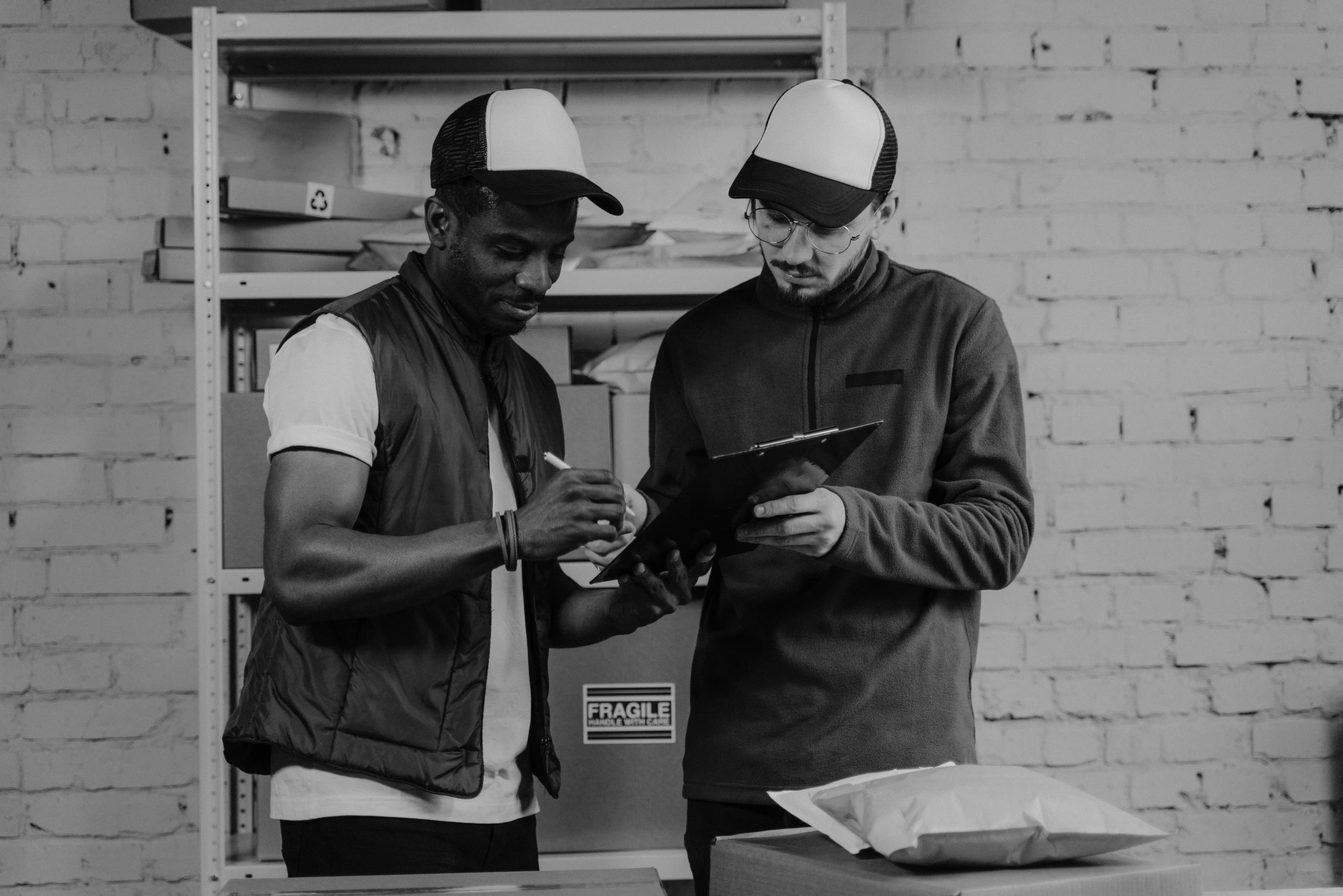 a couple of men standing next to each other, a black and white photo, pexels, arbeitsrat für kunst, writing on a clipboard, inspect in inventory image, with rap cap on head, mkbhd