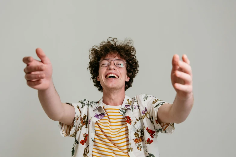 a man that is standing up with his hands in the air, an album cover, pexels contest winner, happening, he has short curly brown hair, goofy smile, portrait featured on unsplash, patterned clothing