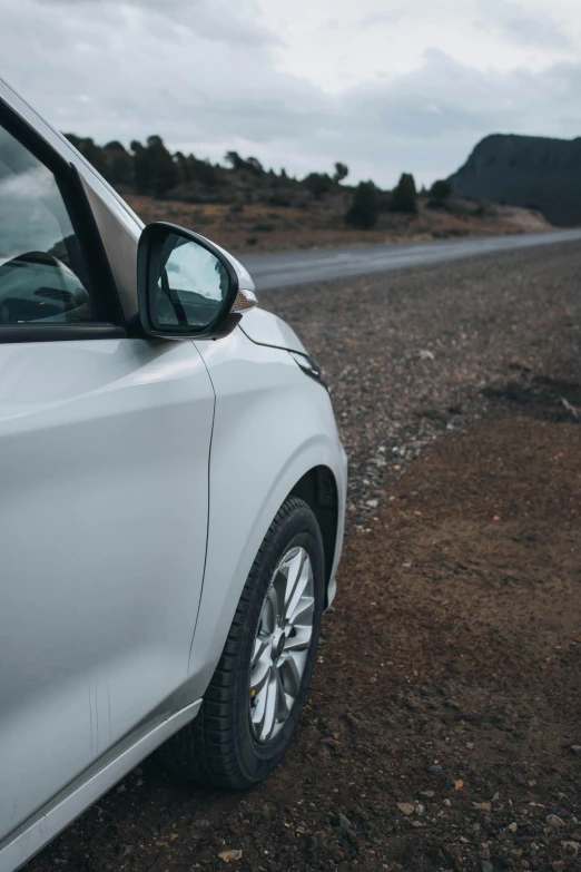 a car is parked on the side of the road, up close, looking off to the side, white metallic, exploration