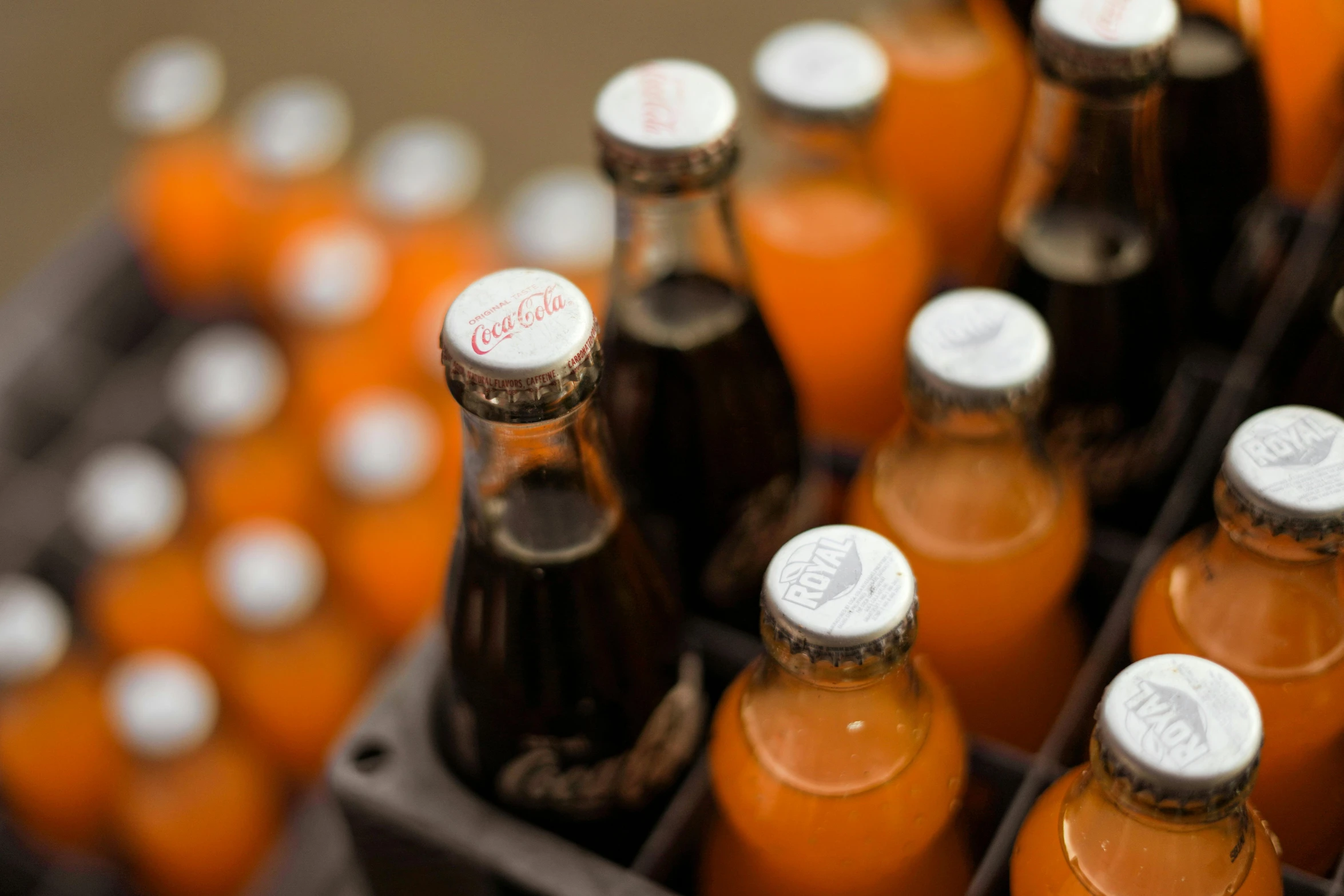 a crate filled with bottles of orange juice, a tilt shift photo, pexels, pop art, coca cola logo, closeup photograph, brown, small